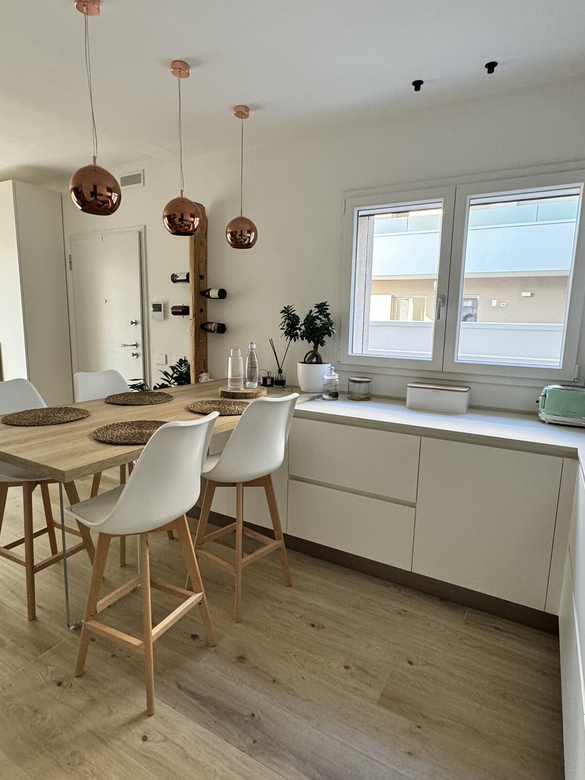 Cucina moderna in legno con parquet e sedie alte bianche